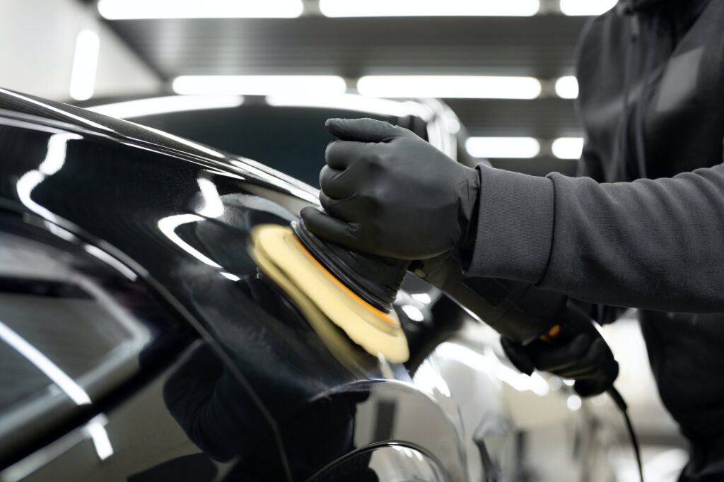 Professional detailing a car in car studio, hands with orbital polisher, scratching remover.